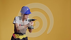 Female constructor working with power drill electric tool