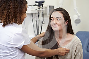Female Consultant Examining Teenage Patient In Hospital