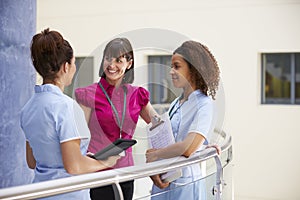 Female Consultant Meeting With Nurses Using Digital Tablet