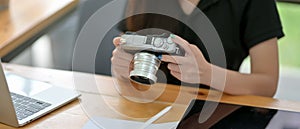 Female content creator looking image on camera while sitting at wooden worktable