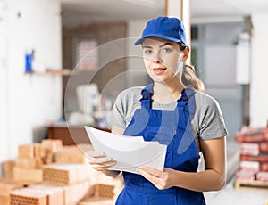 Female contractor checking blueprints and taking notes at building site