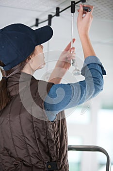 female contractor installing suspended light