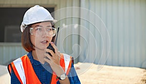 A female contractor is talking on a walkie-talkie