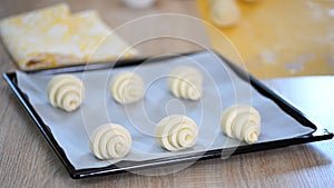 Female cook arranging croissants on a cooking tray at the kitchen. Cooking farinaceous foods in a bakery.