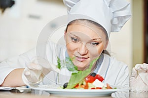 female cook chef decorating prepared salad food