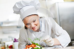 Female cook chef decorating prepared salad food