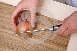 female cook cuts onions on a wooden board in a white apron in her kitchen