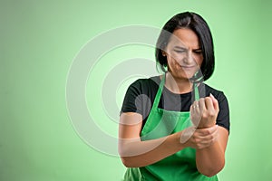 Female cook with green apron and black t-shirt has wrist pain