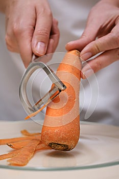 female cook peeling carrots hands close-up