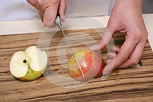 female cook slices an apple on a wooden board in her kitchen