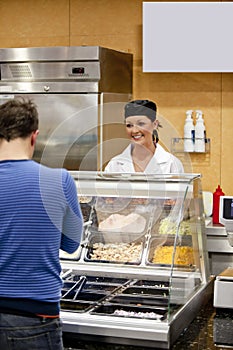 Female cook waiting for a student to choose food