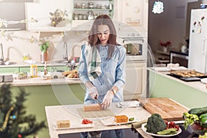 Female cook working in gloves making Japanese sushi rolls slicing them on bamboo mat standing in kitchen