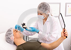 Female cosmetician consulting man before facial treatment
