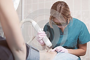 Female cosmetician doing foot therapy using laser