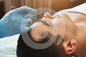 Female cosmetician using blackhead remover