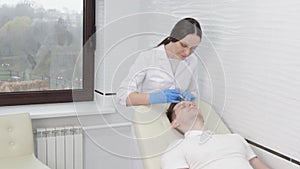 A female cosmetologist in the clinic injects carbon dioxide into the skin of a male client to increase blood flow in the