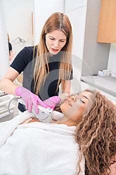 Woman cosmetologist performs a smas-lifting procedure on the decollete area photo