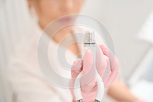 Female cosmetologist holds in his hand apparatus for skin resurfacing procedure