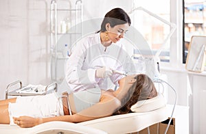 Female cosmetologist performing facial skin cleansing with ultrasonic shovel on woman