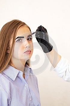 Žena kosmetolog vykonává obočí oprava na krásný v krása. hnědý vlasy 