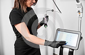 Female cosmetologist using radiofrequency microneedling machine.