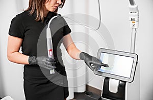 Female cosmetologist using radiofrequency microneedling machine.
