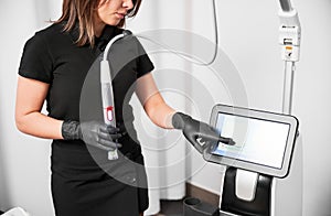 Female cosmetologist using radiofrequency microneedling machine. photo