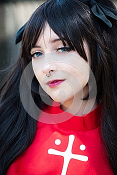 Female cosplayer with black hair in a black skirt and red shirt with a cross on it