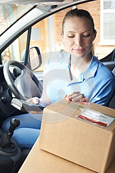 Female Courier In Van Delivering Package To Domestic House