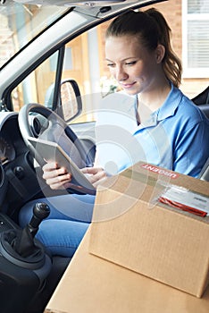 Female Courier In Van With Digital Tablet Delivering Package To