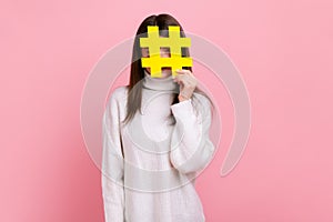 Female covering face with social media hashtag symbol, recommending to follow trendy content, blog.