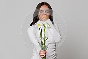 Female covering her nose, having an allergic reaction to flowers chamomile, selective focus. Allergy