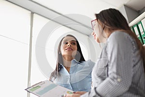 Female coworkers discussing report business growth and statistics