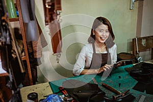 Female craftswoman smiling at the camera while making leather apron