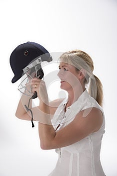 Female cricketer putting on safety helmet