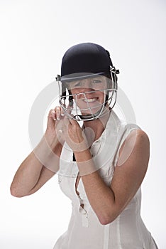 Female cricketer putting on safety helmet