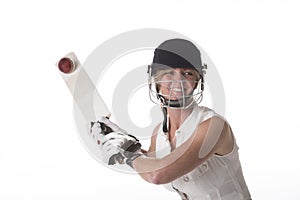 Female cricketer in safety helmet hitting a ball