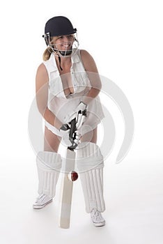 Female cricketer in a white dress with bat, pads, bat and safety helmet.