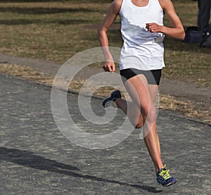 Female Cross Country runner racing on a gravel path