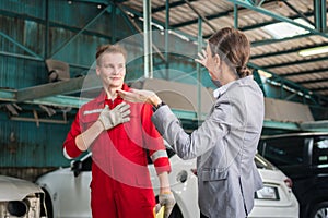 Female customer and car mechanic in auto repair shop, Woman customer and mechanic discussing repairs done to her vehicle