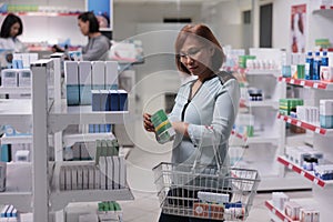 Female customer examining vitamins box on shelves