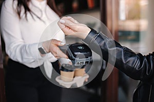 Female customer making wireless or contactless payment using smartwatch. Cashier accepting payment over nfc technology