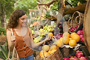 Female Customer At Market Stall Choosing Fresh Fruit And Vegetables