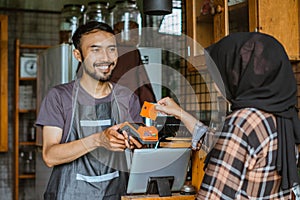 a female customer paying using the credit card at the coffee shop