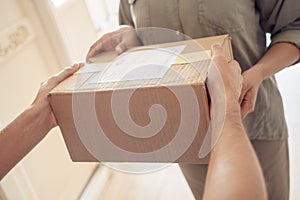 Female customer receiving courier service delivery parcel box at home, close up.