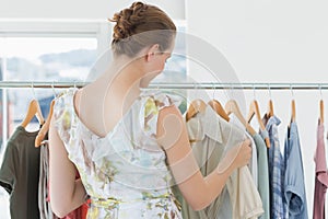 Female customer selecting clothes at clothing rack in store