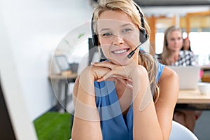 Female customer service executive with headset looking at camera in a modern office