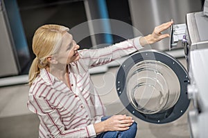 Female customer in striped shirt choosing a washing machine in megastore