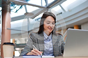 Female customer support operator with headset and smiling.