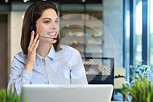 Female customer support operator with headset and smiling.